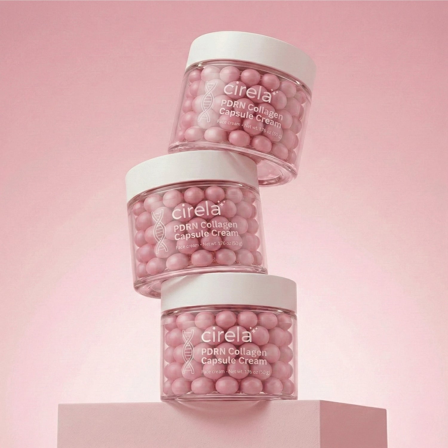 Three clear jars of Cirela PDRN Collagen Capsule Cream, each filled with pink capsules, are stacked on a pink surface with a pink background.